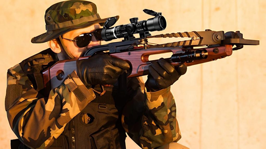 A person in camo gear, tactical gloves, and sunglasses aims a crossbow with a HILIYOT crossbow scope.